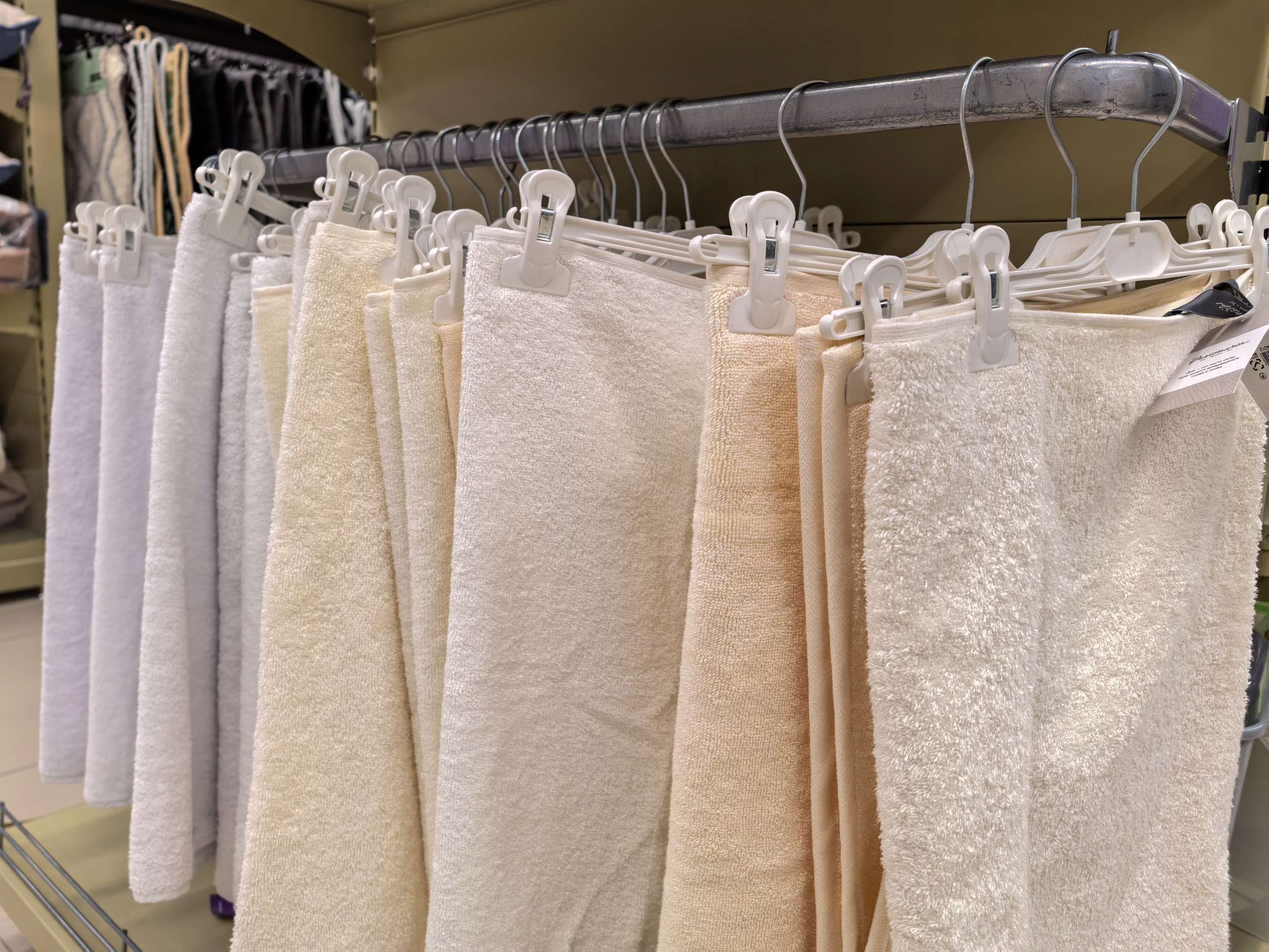Soft Cotton Bath Towels in Neutral Colors Hanging on Display Rack in Store